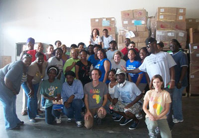 Tired but enthusiastic Americorps group relaxed and posed for a photo with warehouse staff after their busy morning.