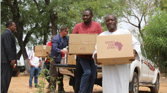 Garoua Linguistic Center staff and students work with CAT 4032 to unload donated books